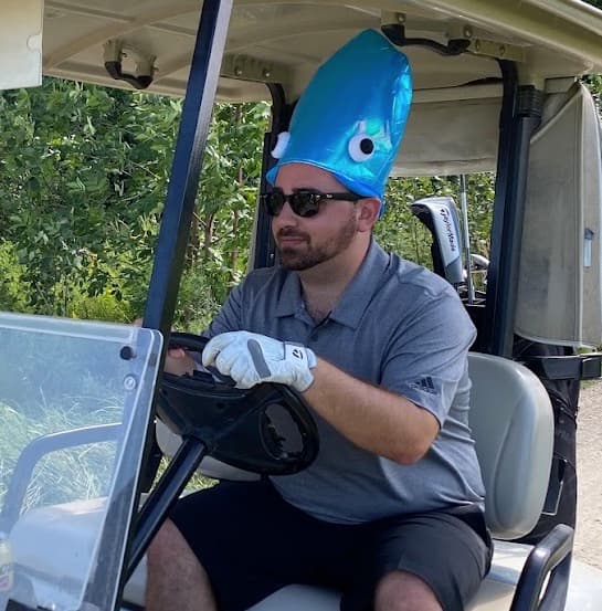 Dave wearing a blue squid hat in a golf cart
